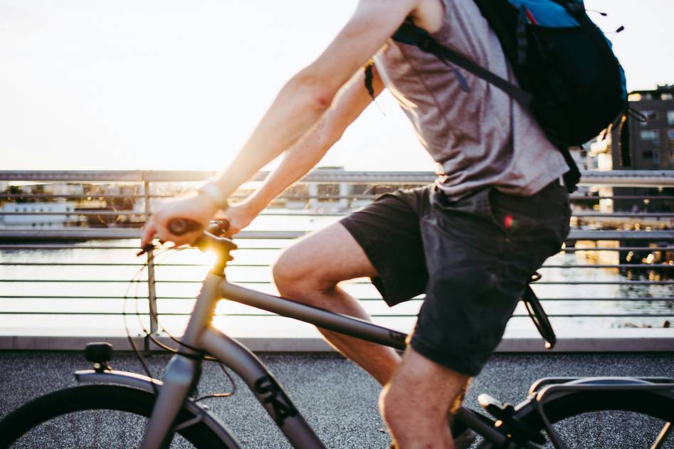 Woman smiling on her bike after a morning ride, holding a water bottle and wearing workout clothes
