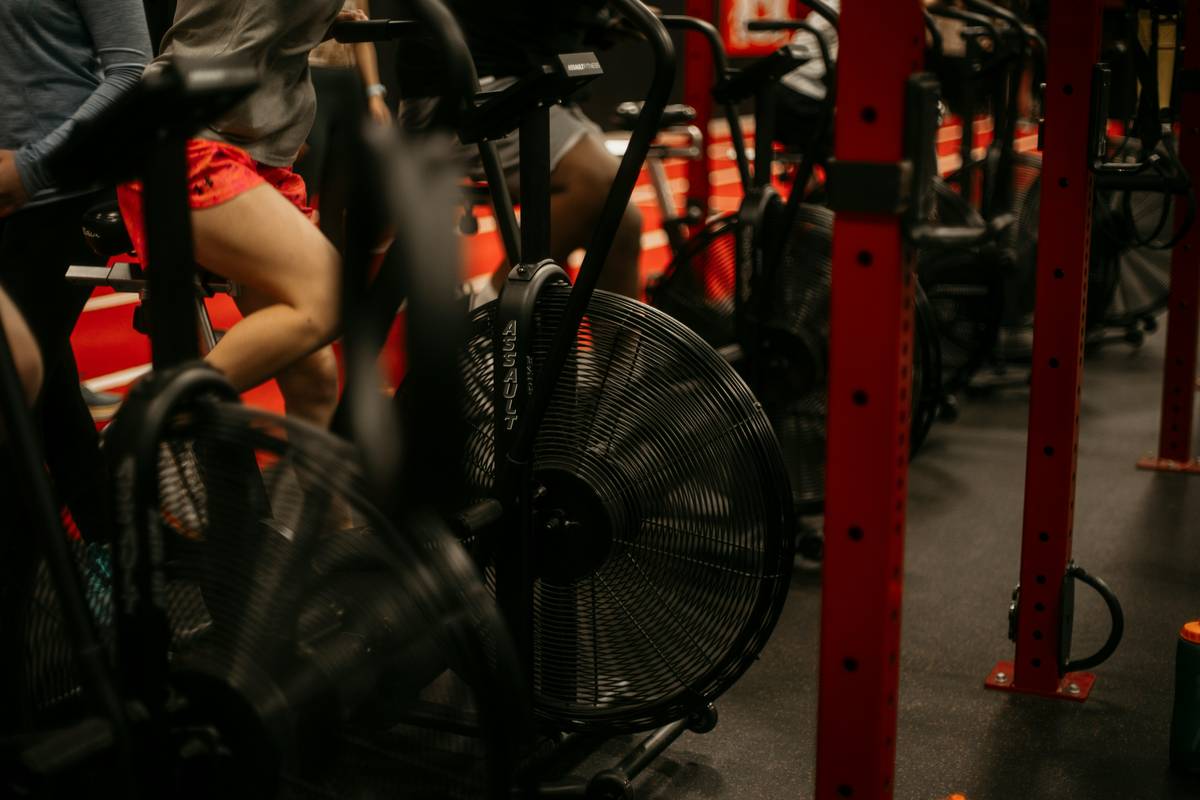 Woman cycling indoors during a spin class, sweating but smiling — spin slim cycling how long doe