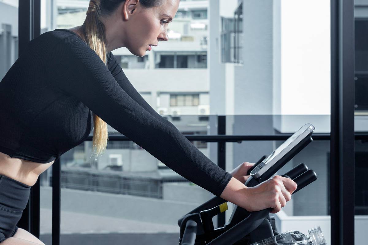 Woman cycling outdoors with printed cycling pdf for weight loss tucked in her handlebar bag